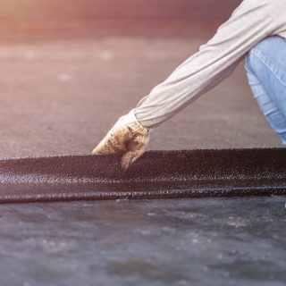 Group of worker installing tar foil on the rooftop of building. Waterproof system by gas and fire torching A close-up view of a high-quality black rubber roof being installed on a low-slope home addition