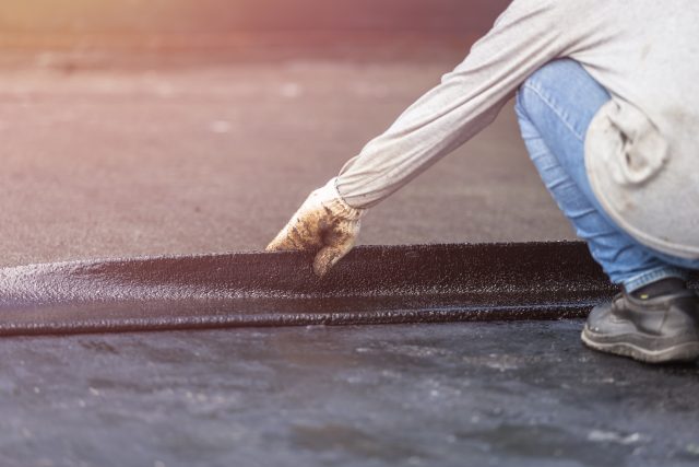 A close-up view of a high-quality black rubber roof being installed on a low-slope home addition